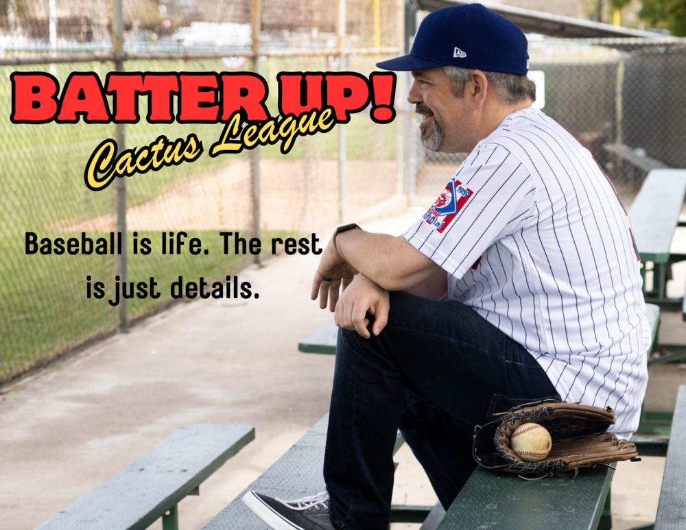 A man in a blue baseball cap and a white pinstriped jersey sits on a bench at a baseball field, leaning forward with a smile. His right arm rests on his knee, and a brown leather baseball glove with a baseball inside sits beside him on the bench. The background features a chain-link fence and a baseball diamond. The image includes bold red and yellow text reading "BATTER UP! Cactus League" at the top, and below it, black text stating, "Baseball is life. The rest is just details."